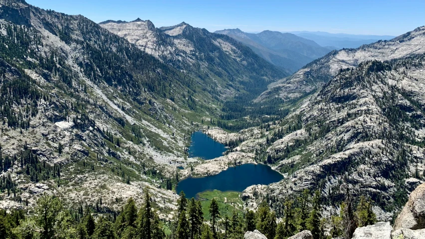 large mountain side with lake surrounded by pine trees