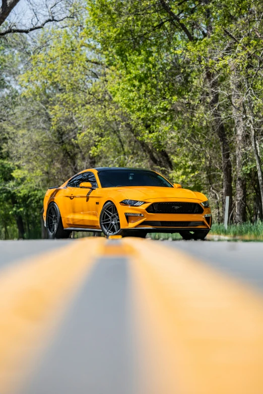 the yellow sports car is shown on a road