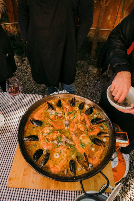 the people is standing behind the big seafood pizza