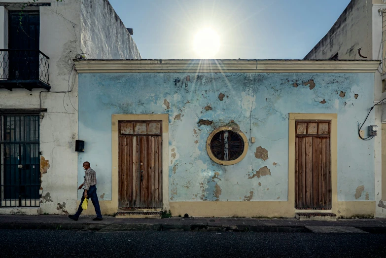 an older man walks past a weathered building