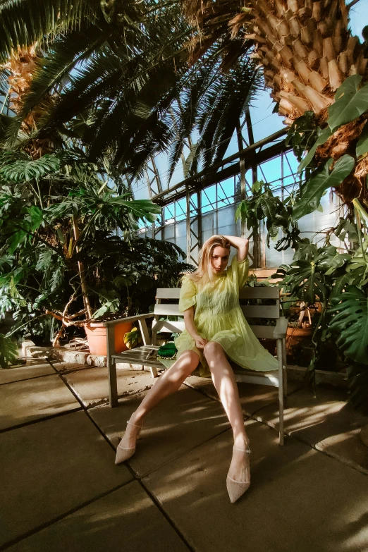 a woman posing in a tropical setting while sitting on a bench