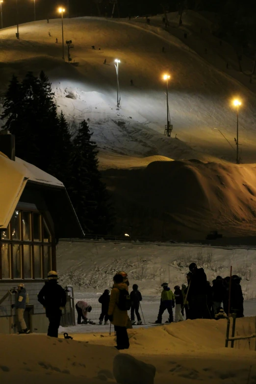 several people standing around a snowy slope at night