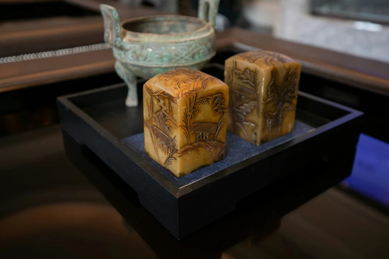 two pieces of carved and etched wood on a black plate