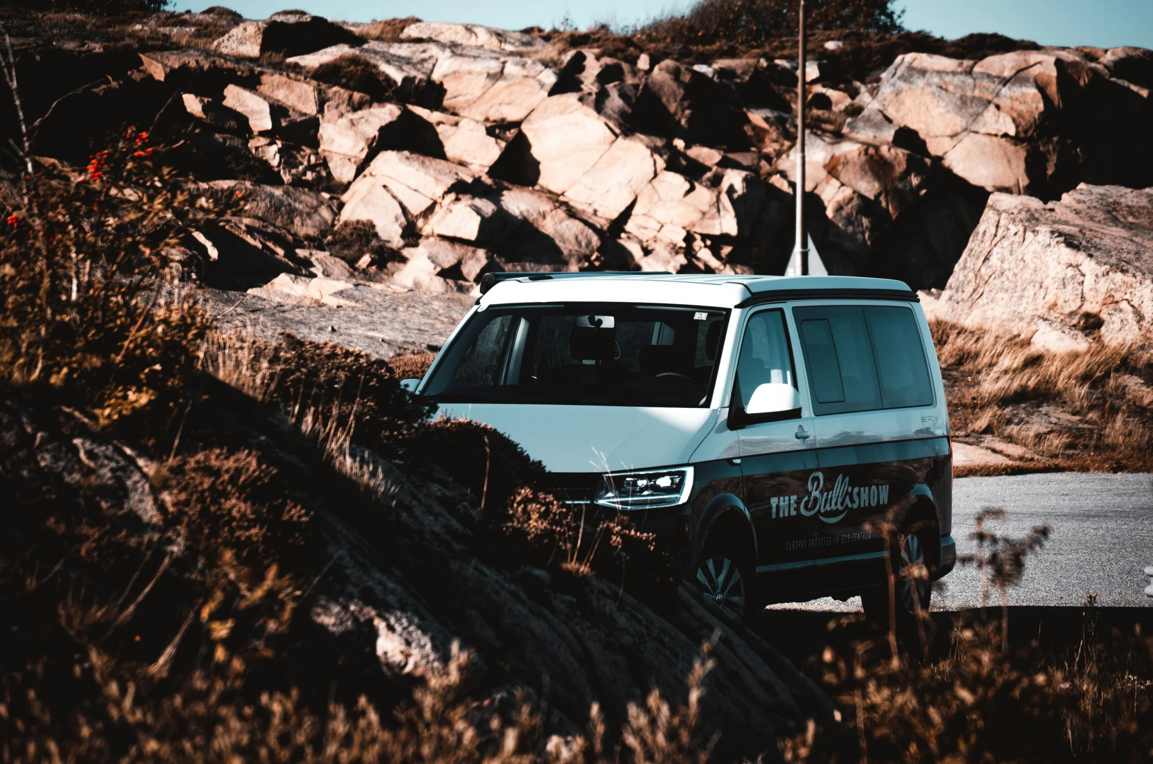 a van parked on a street near a rocky hill