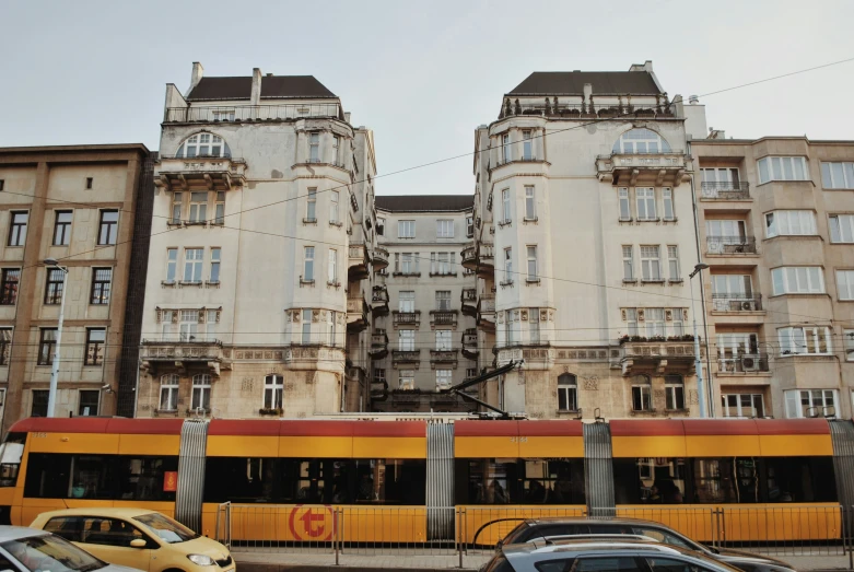 the yellow and red bus is near some buildings