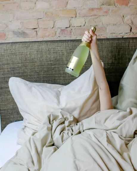 the woman in bed is holding up a champagne bottle with her foot