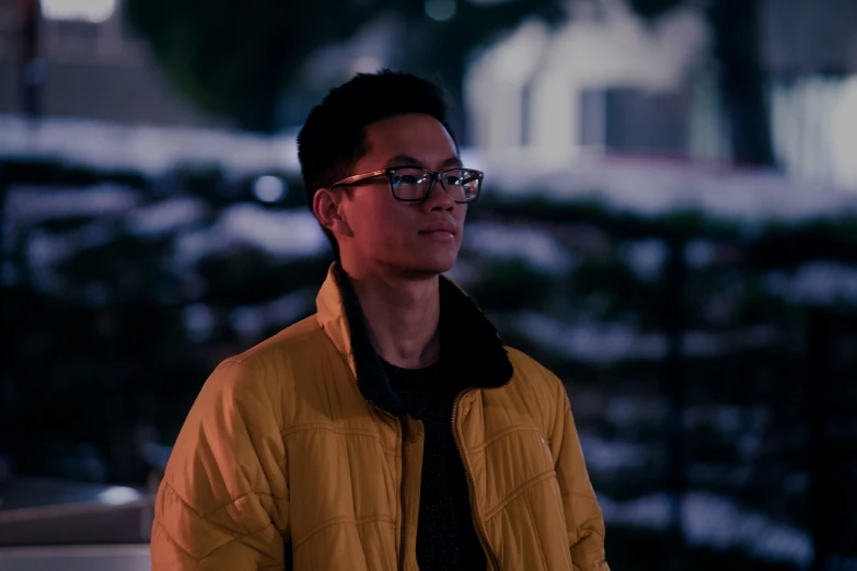 a man with glasses, wearing a yellow coat and black tie