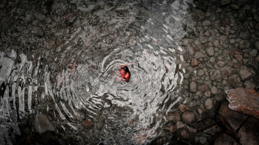 a man swimming in a river with rocks surrounding him