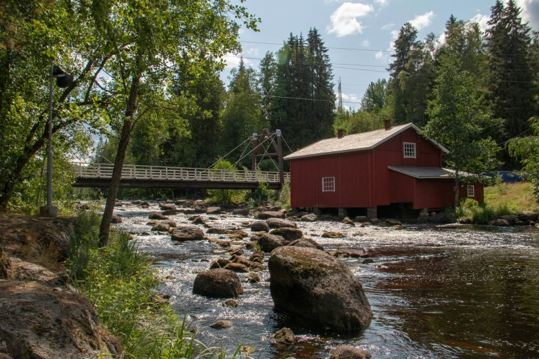 there is a small red building sitting next to a river