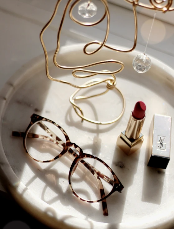 a table with eye glasses, lipstick and golden necklace