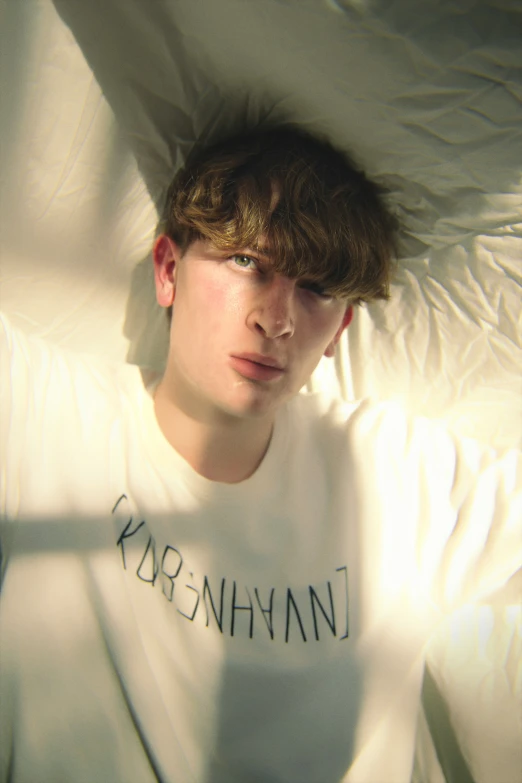 young man lying on bed with text tee shirt