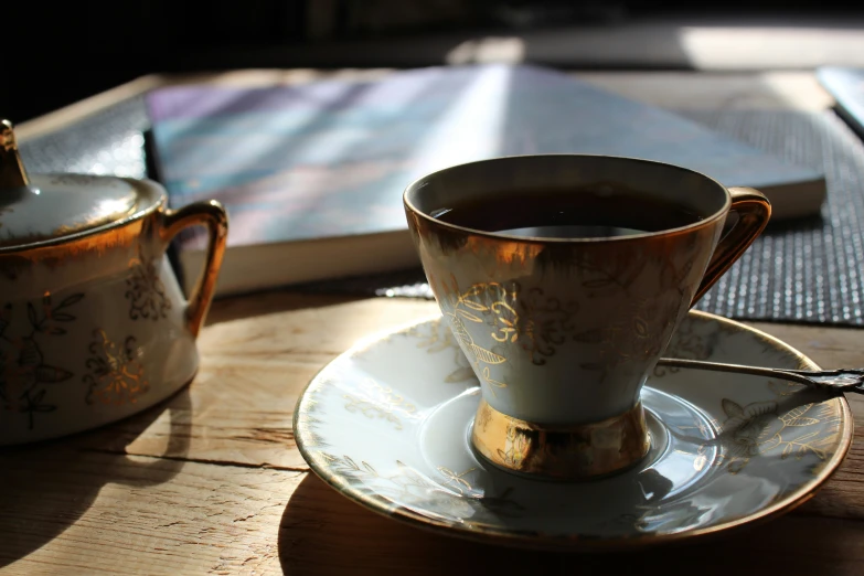 a teacup is on a saucer next to a book