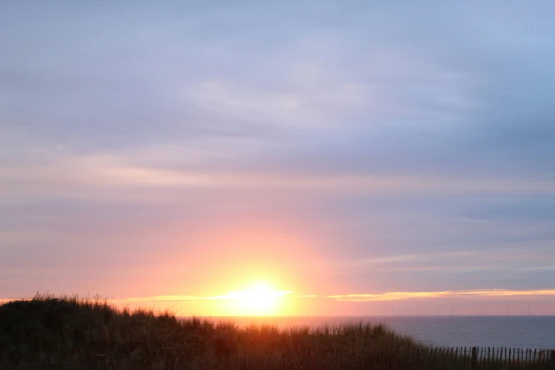 sunset, with a surfboard and a fence