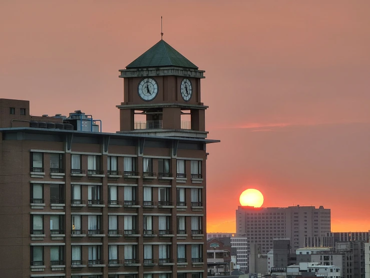 a clock tower in the city with sunset behind it