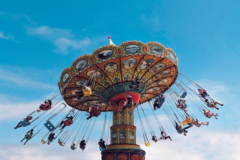 people ride on a carousel in the park