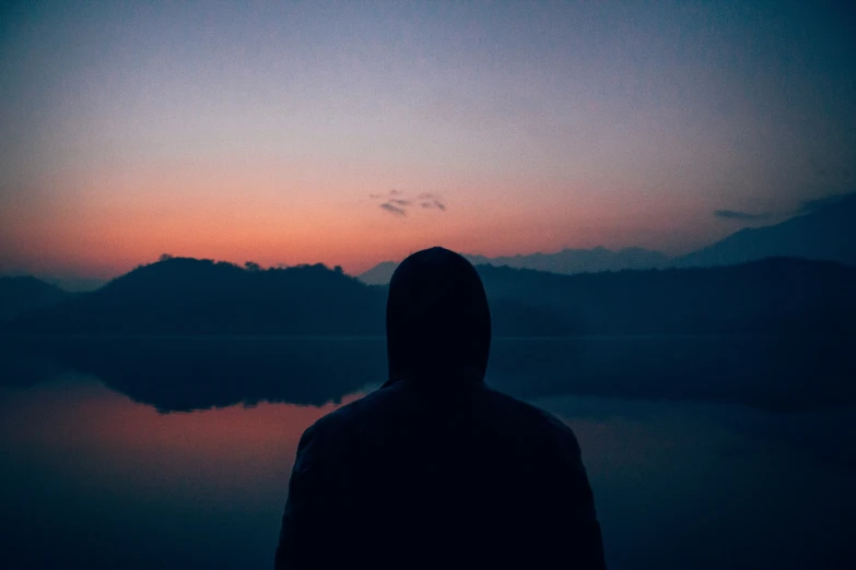 a man in black jacket standing by a body of water