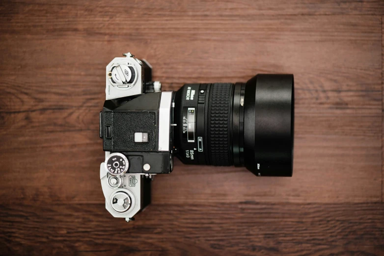 a camera on a wooden table with a lens attached to the top of it