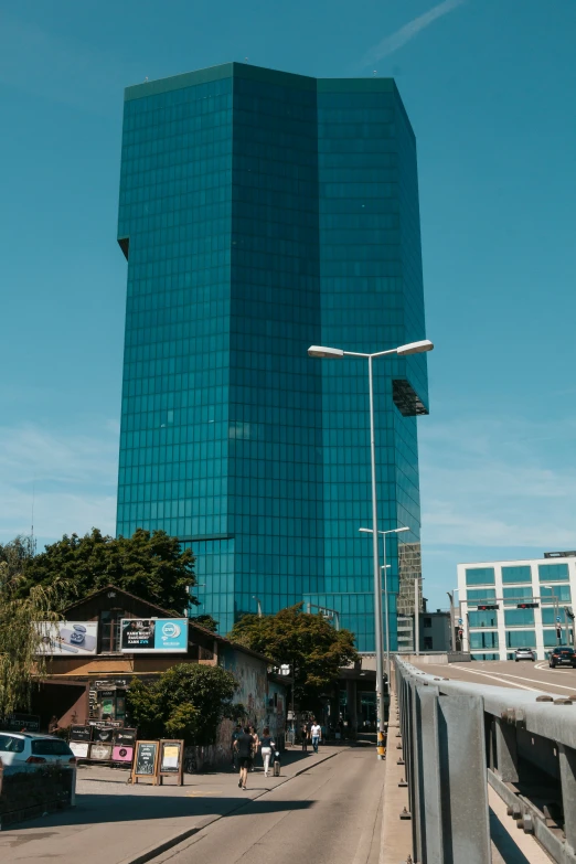 some people walking on a bridge in front of a very tall building