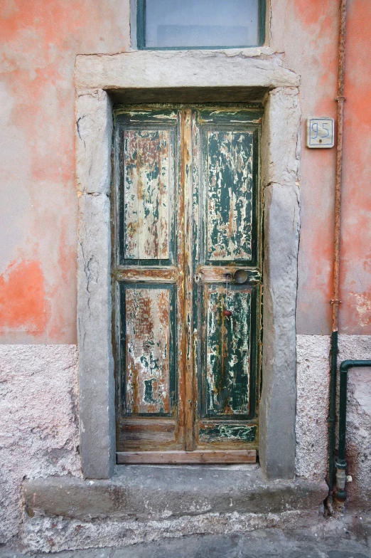 an old door that has been painted red, and has two green latches