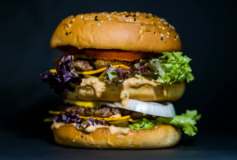 an extremely large hamburger with lettuce and onions