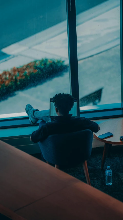 a person sitting in an armchair looking at a window