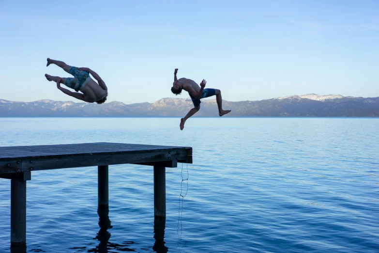 two men jumping off dock into water