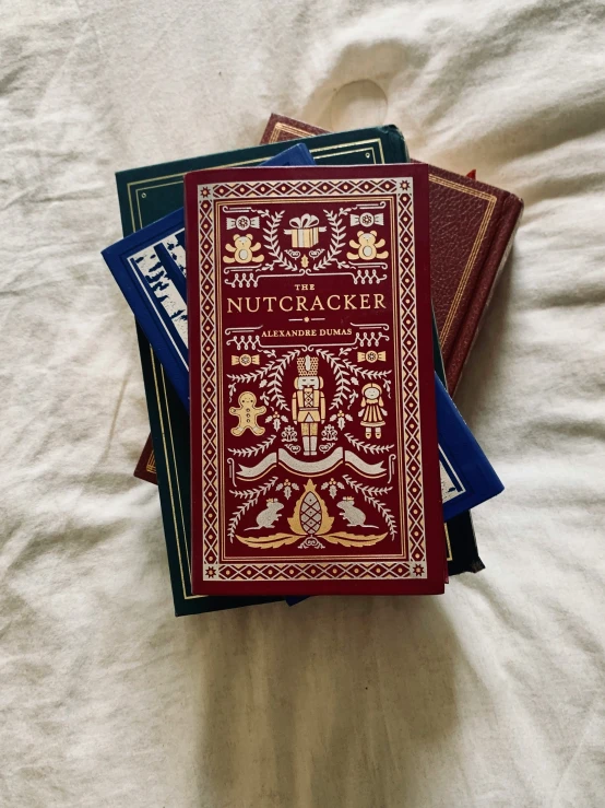 a stack of three books with needle work