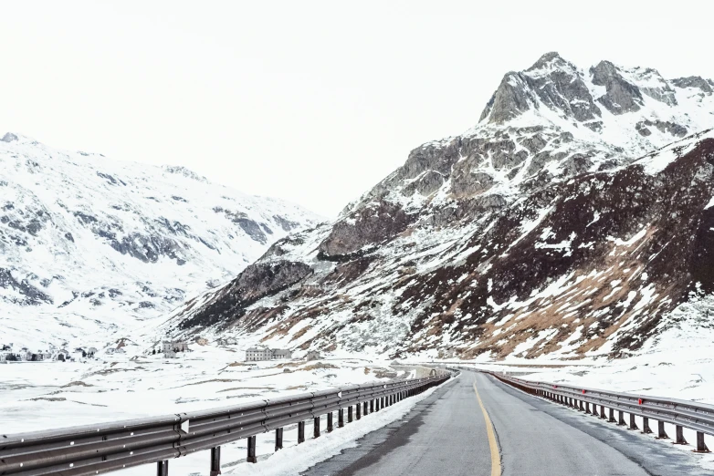 a long road with mountains in the background during winter