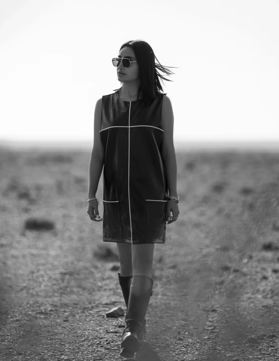 a girl is walking down the beach with sunglasses on