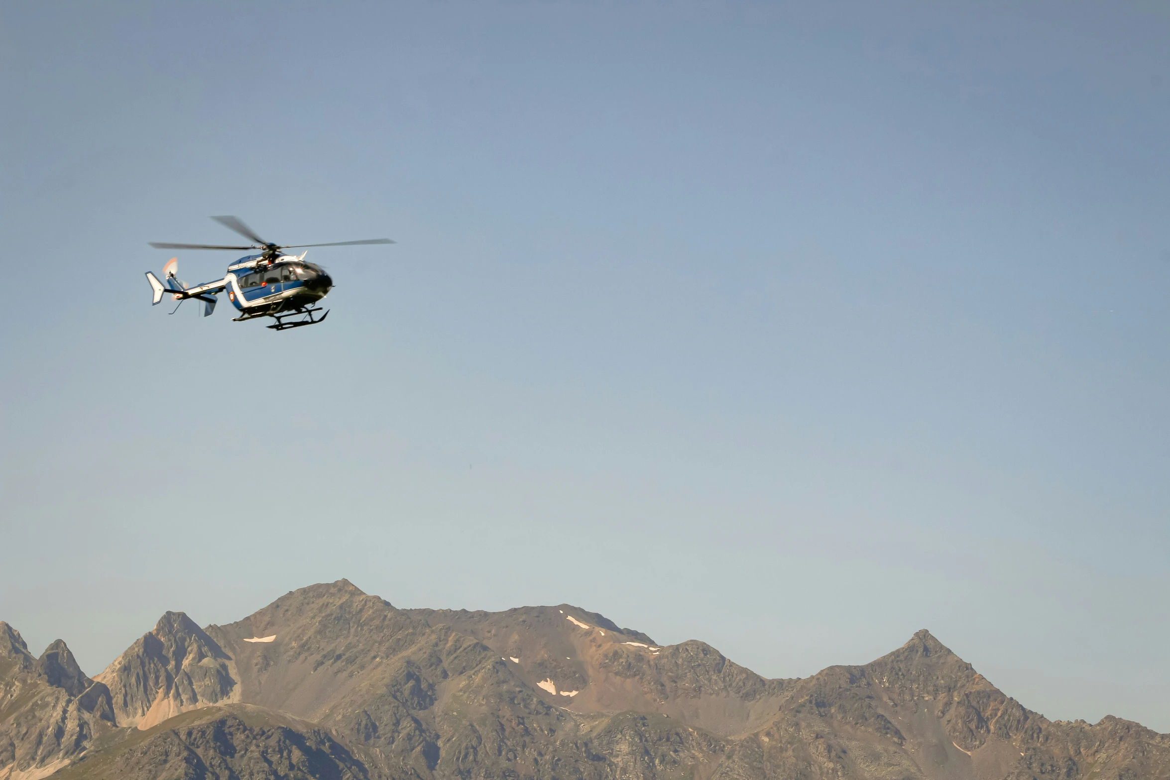 the helicopter is flying over the mountains on the clear day