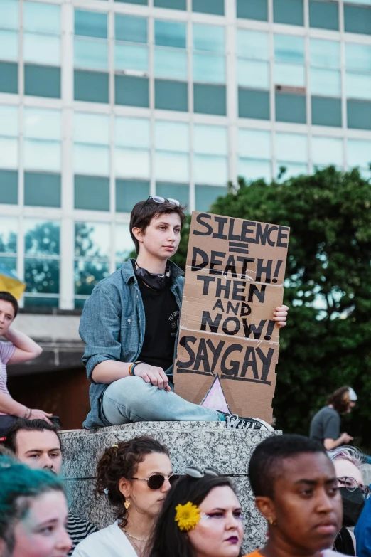 a man holding up a sign while sitting on a stone block