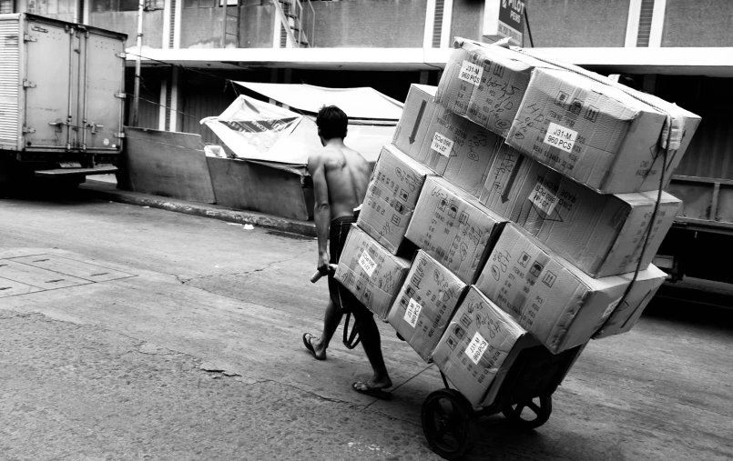 a man riding a bike pulling stack of boxes