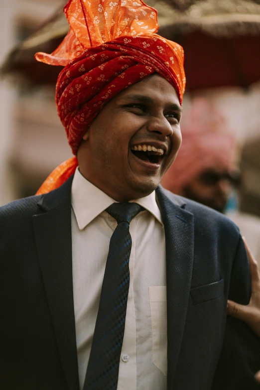 a man wearing an orange turban and tie laughing