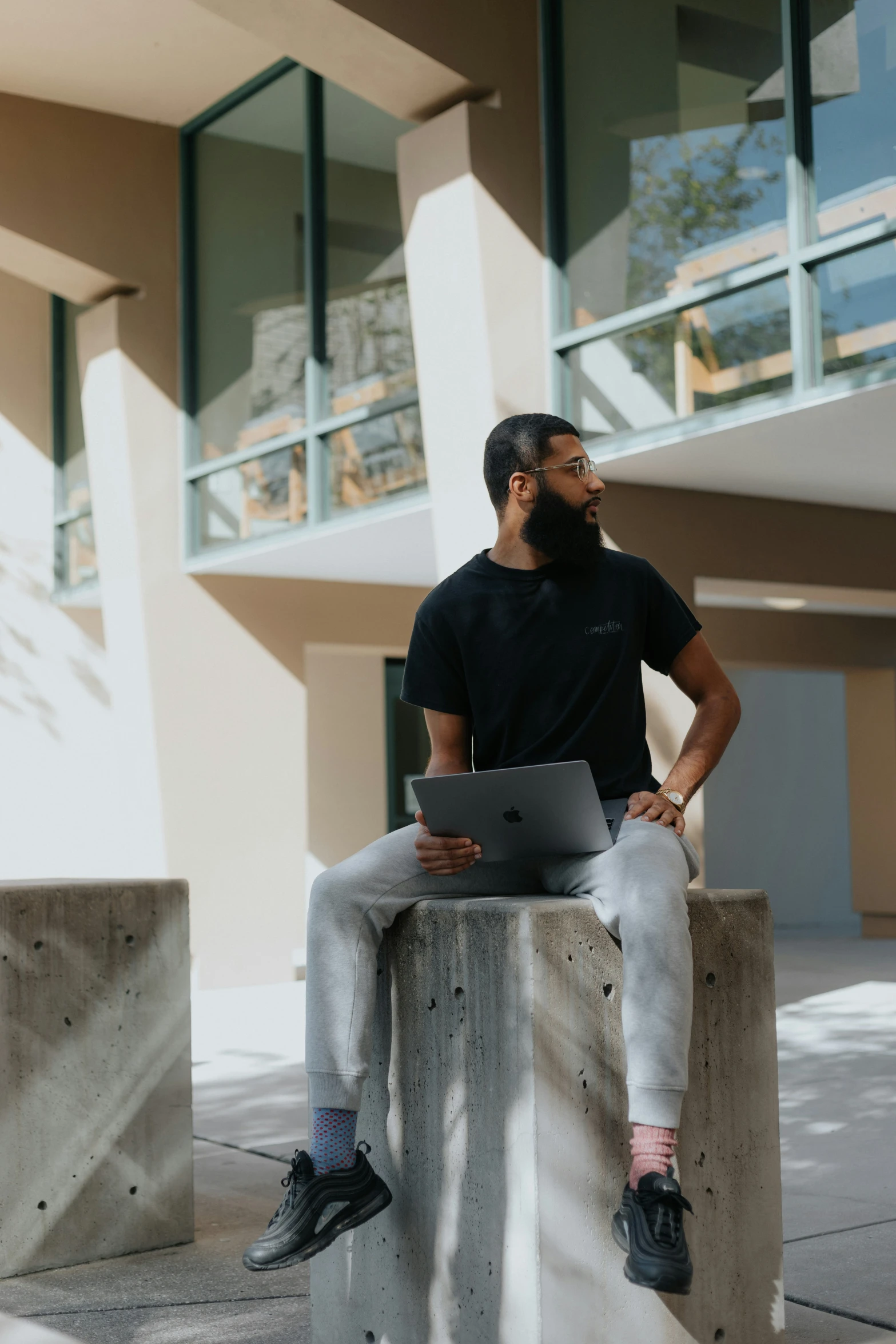 man using a laptop sitting on a bench outside