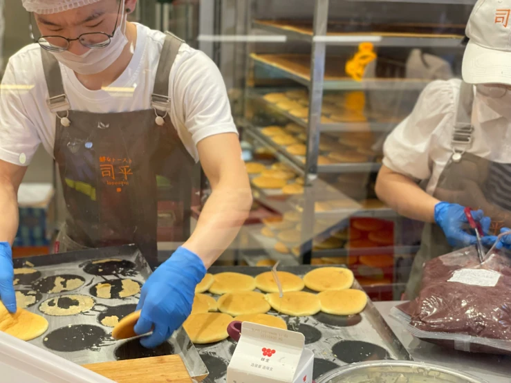 two cooks making cookies behind a bakery counter