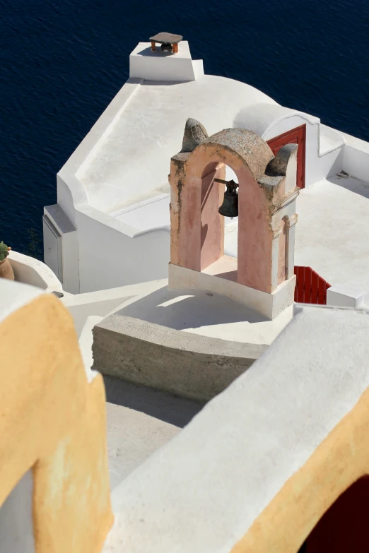 an outdoor bell tower sits in the foreground as a seagull flies overhead