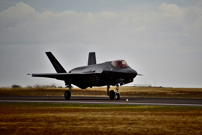 a fighter jet on a runway with sky in background