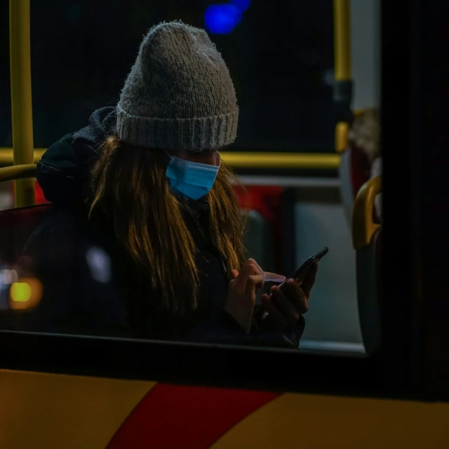 a woman is on a bus and she has a mask to protect her from the cold