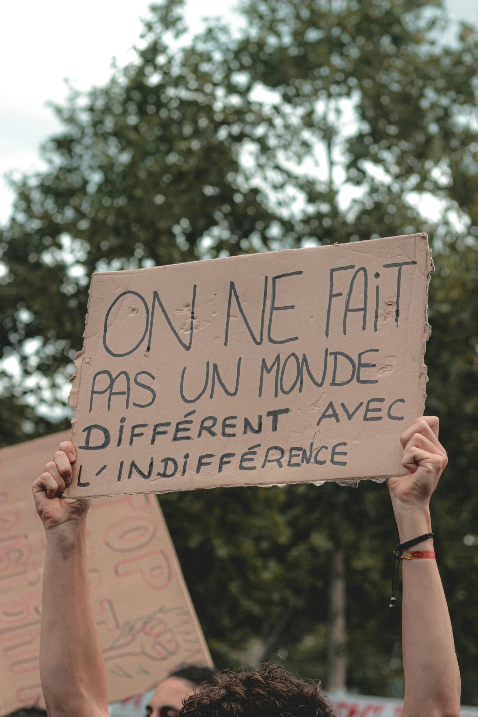 a protester holds a sign that reads on one fat as un mode different avec l'indif efficene