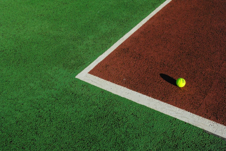 a tennis ball laying on a red tennis court