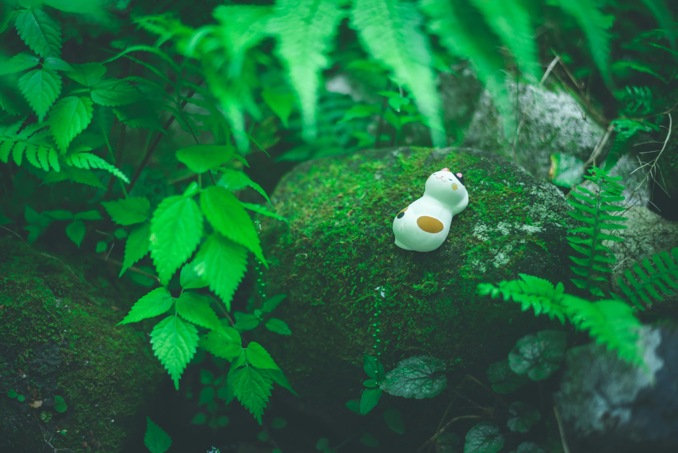 a small white toy is sitting on the moss