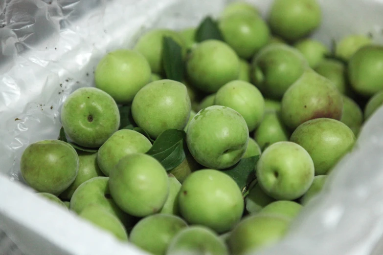 some green apples with leaves in the middle of them