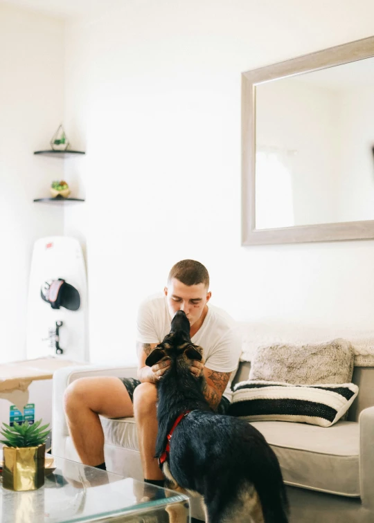 a man is sitting on a couch and pets his dog