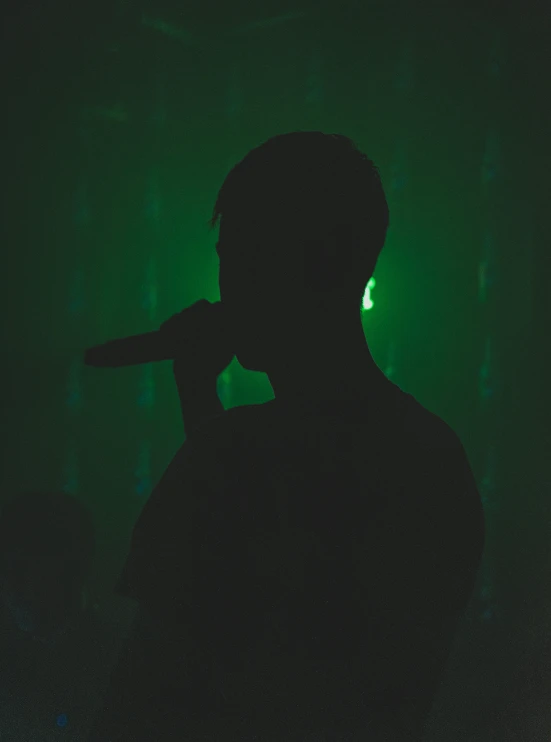 a man in dark holding a microphone and a green dot