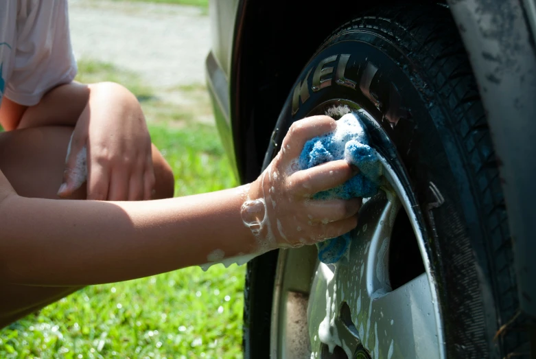 someone washing a car outside using a sponge