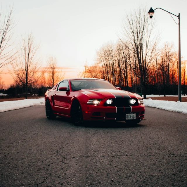 a red sports car is parked at dusk on the road