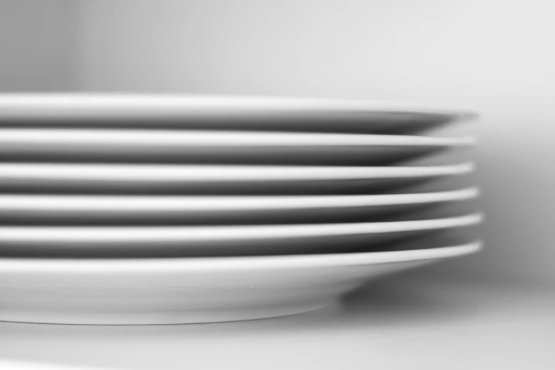 stack of white plates are arranged near a wall