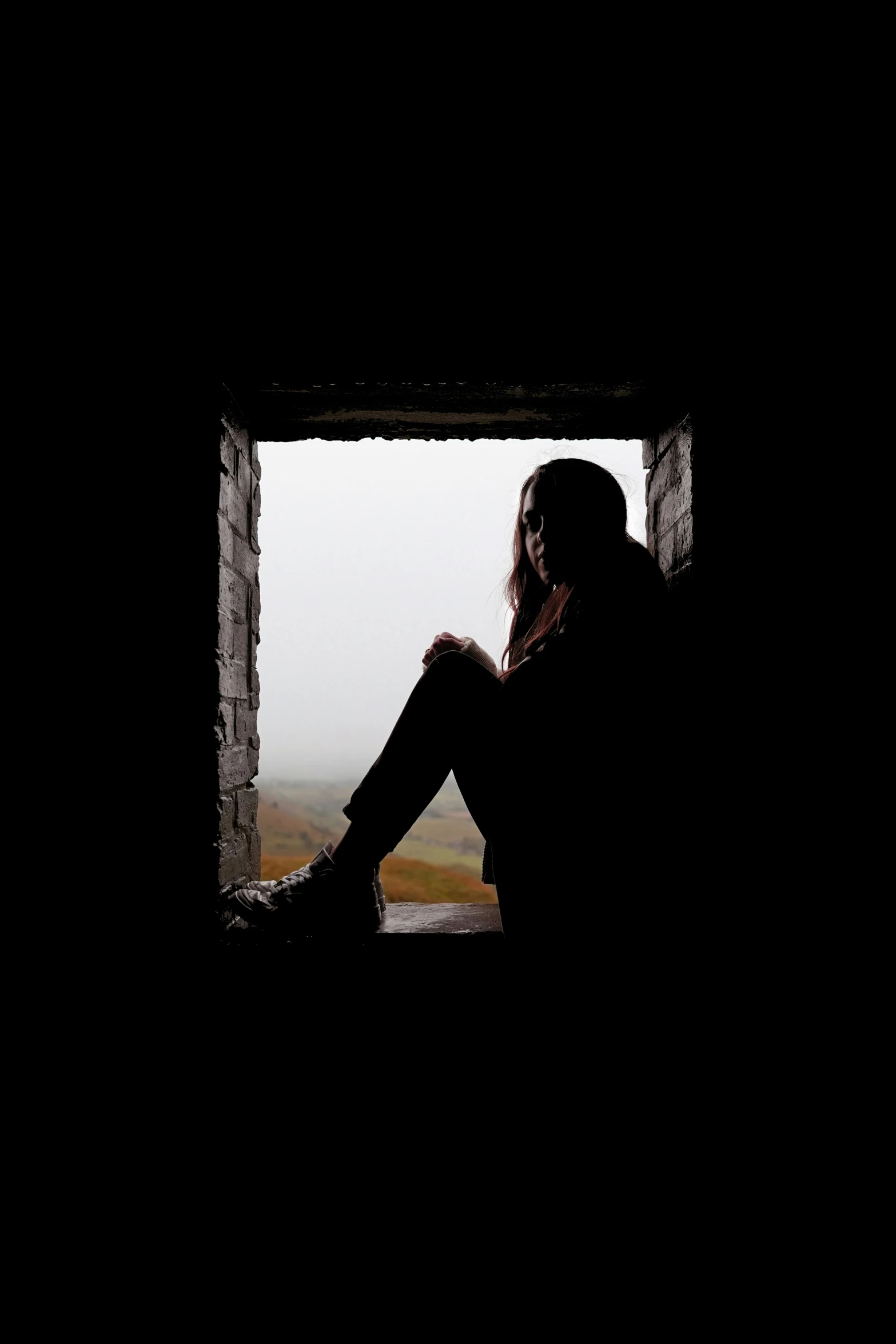 a girl sits in a square window on a mountain