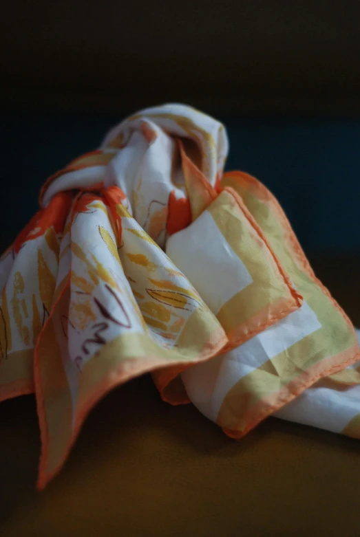 a red and yellow handkerchief sitting on top of a wooden table