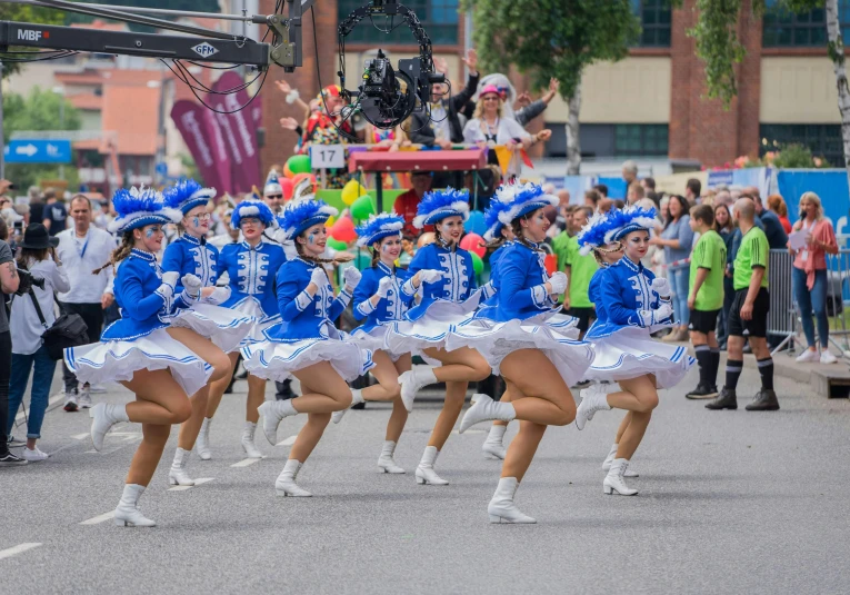 many cheerleaders march in the parade and are dressed in bright blue